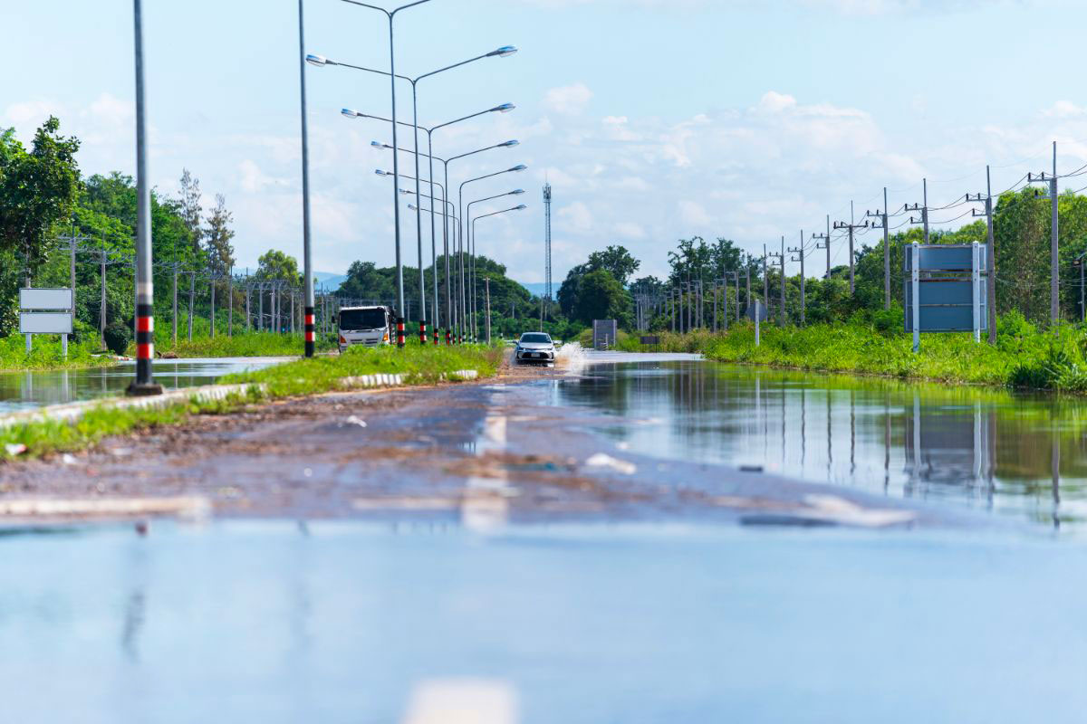 A flooded road with a car struggling through the water.